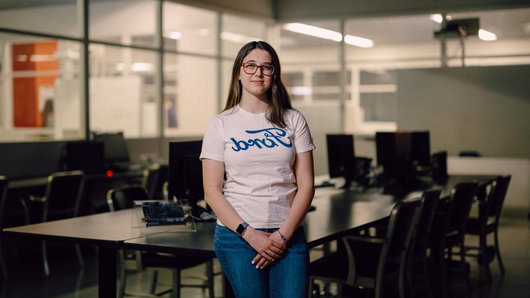 Kettering student Jacqueline Kocik wears a shirt with the Ford logo. She stands in a classroom.